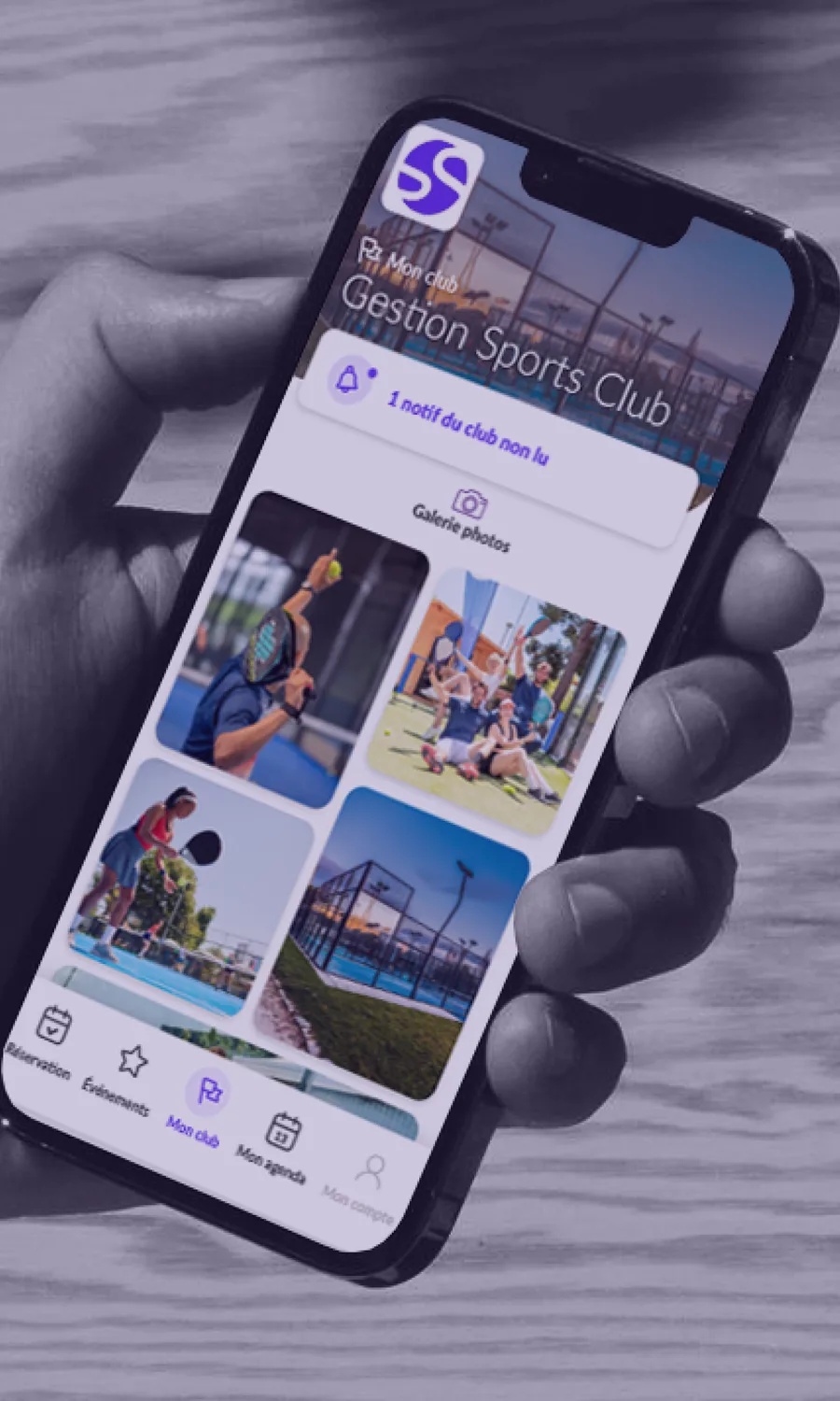 Main tenant un smartphone affichant l'accueil d'une application de club de padel, galerie photos visible